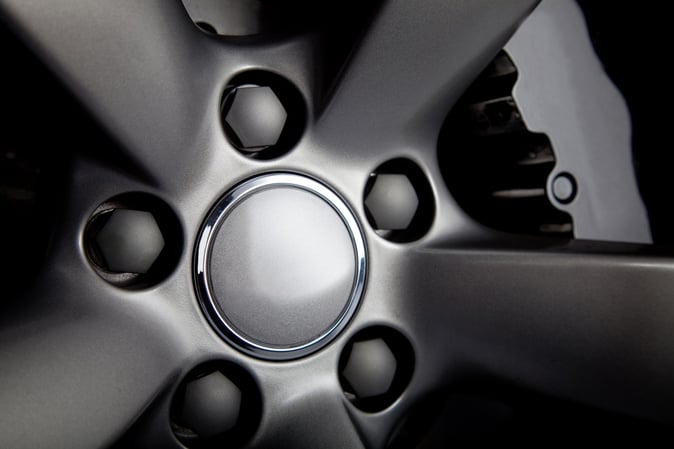Picture of a black car tire with focus on nuts.jpeg